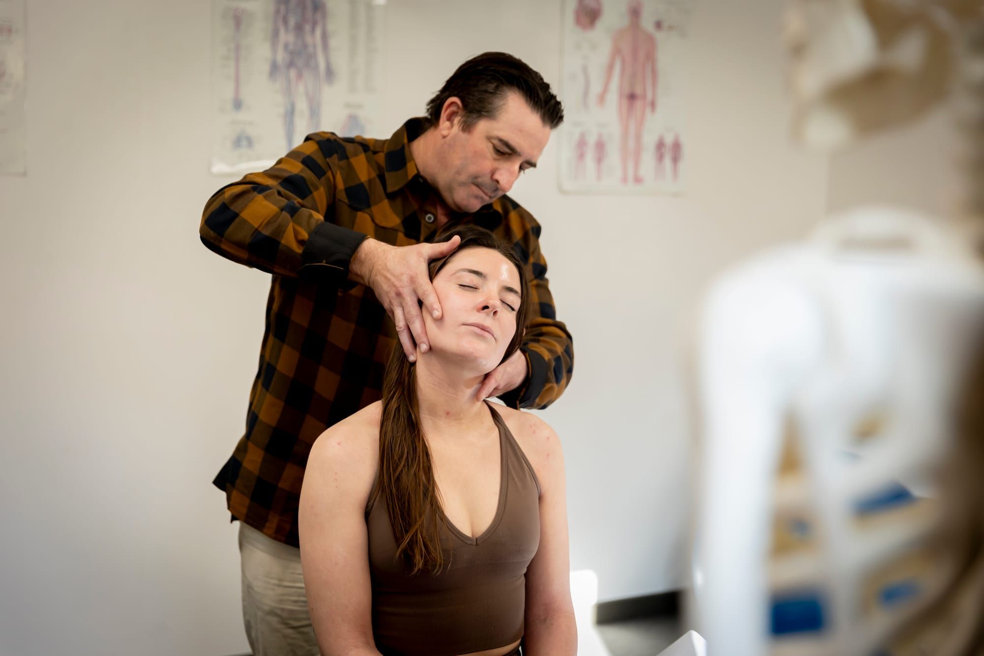 Simon assessing a seated patient's neck in the treatment room